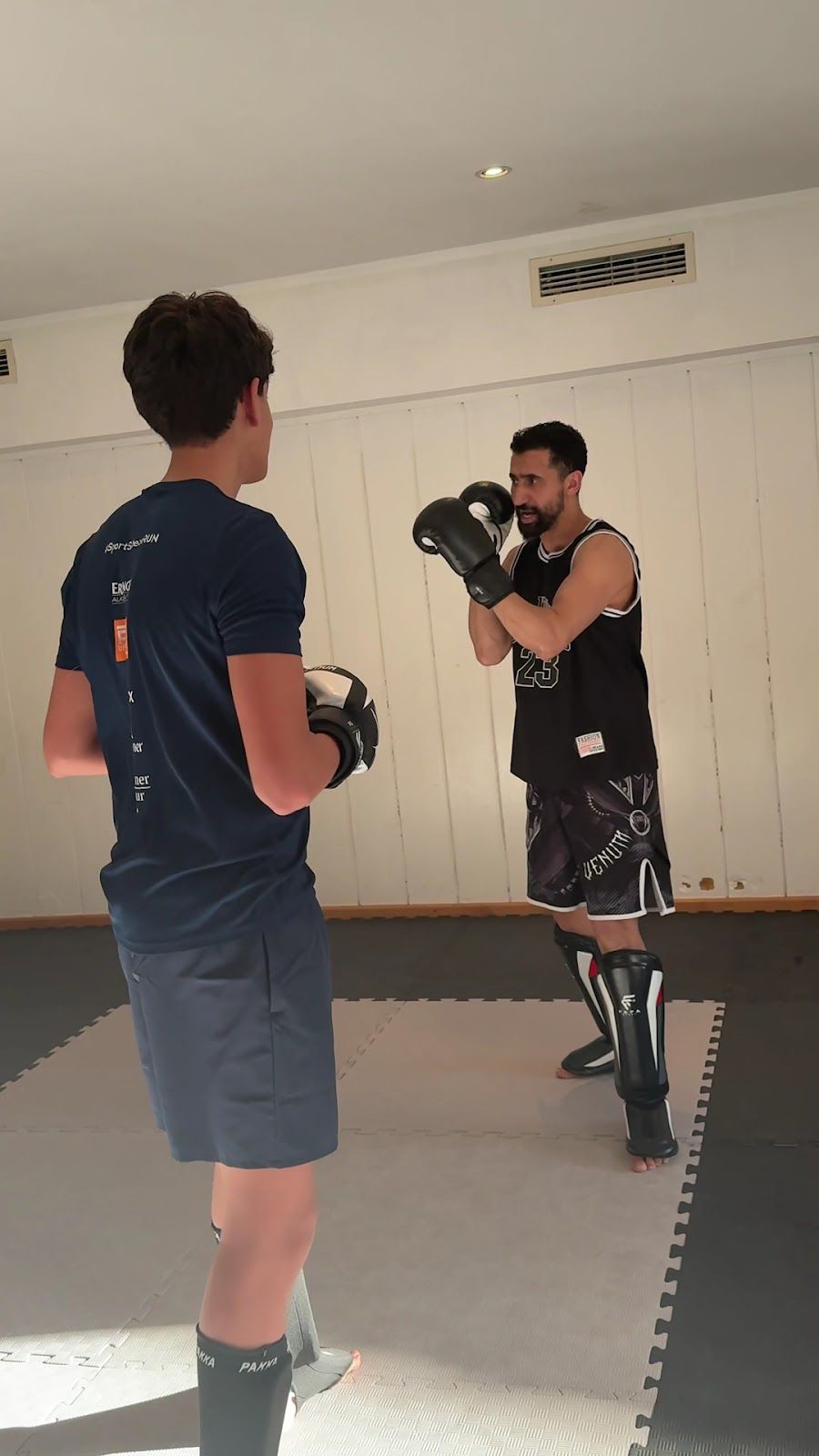 Trainer hält Pratzen für einen Jugendlichen im Techniktraining